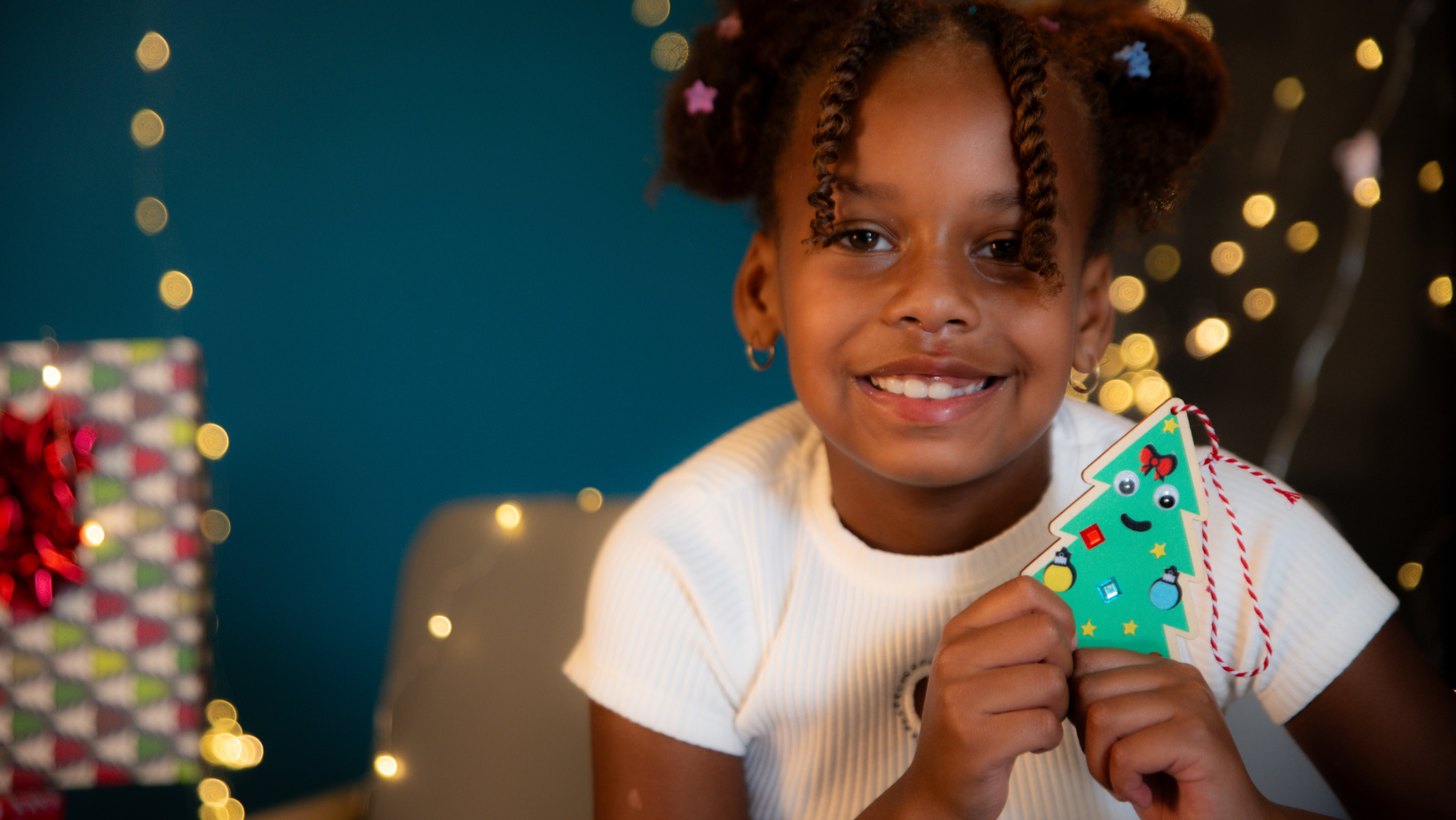 Child smiling with homemade christmas ornament 