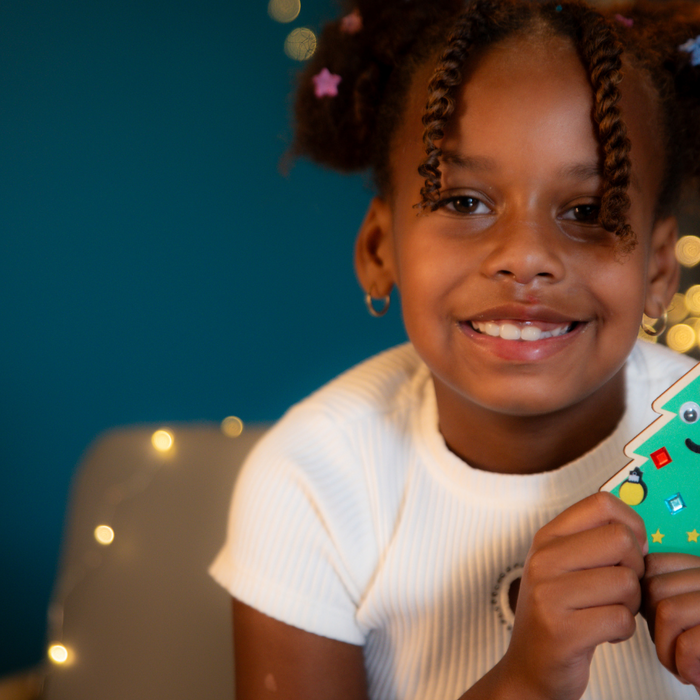 Child smiling with homemade christmas ornament 