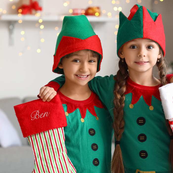 Children dressed as christmas elves holding christmas stockings